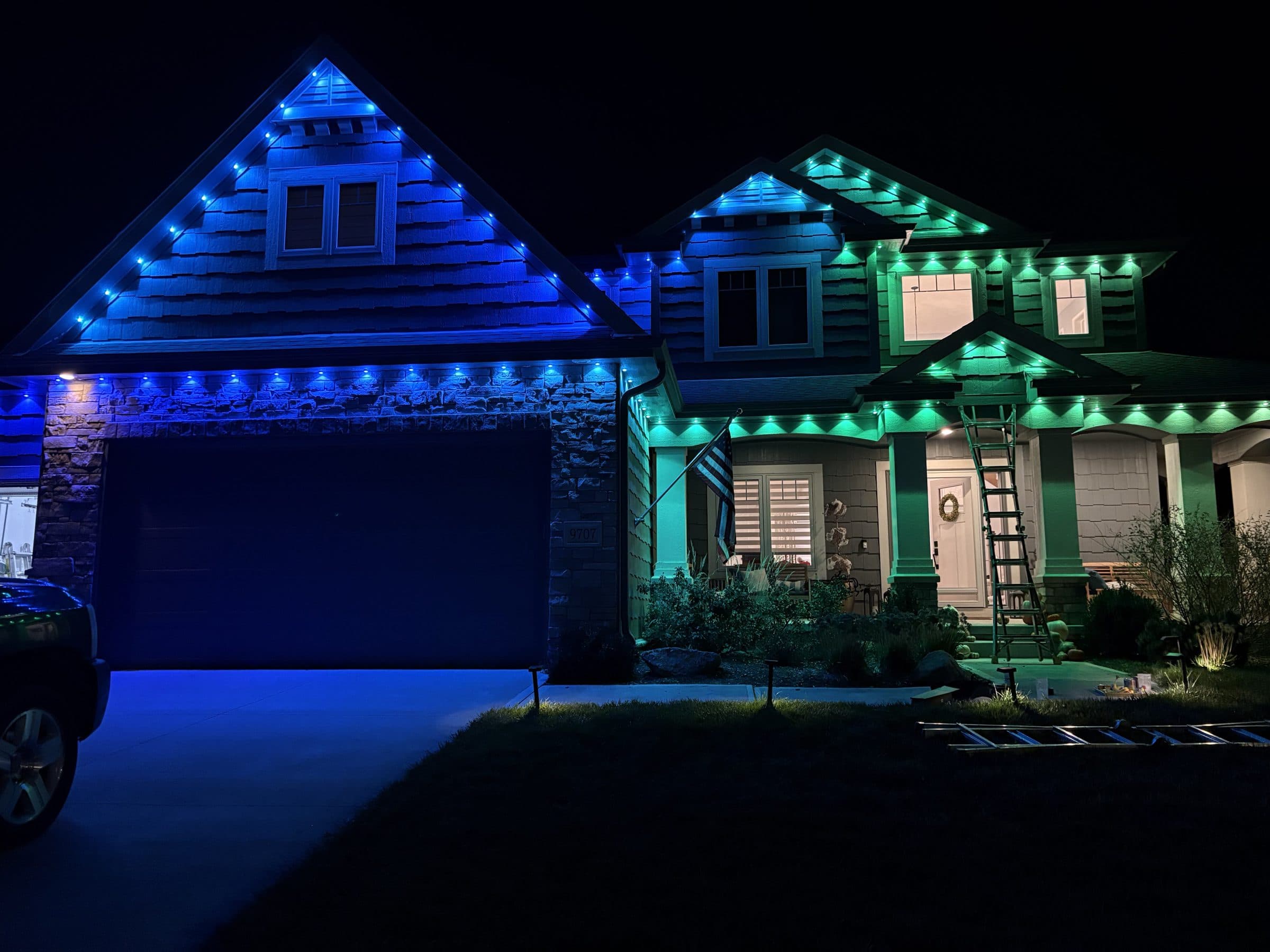 Two story home lit in blue and teal permanent lighting along every gable