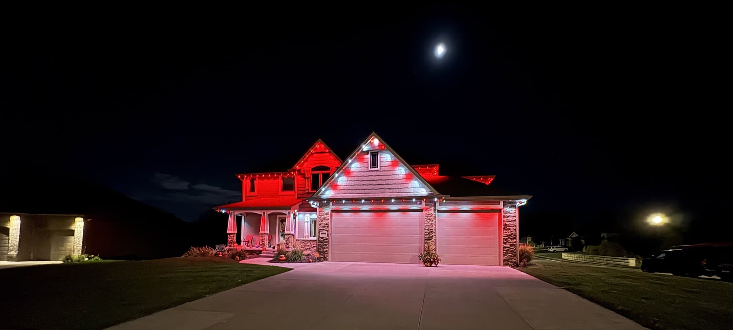 Home lit in red and white under a full moon